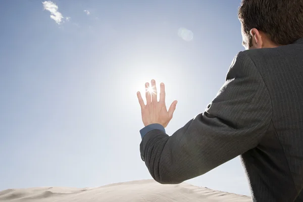 Бизнесмен в пустыне трогает солнечный свет — стоковое фото