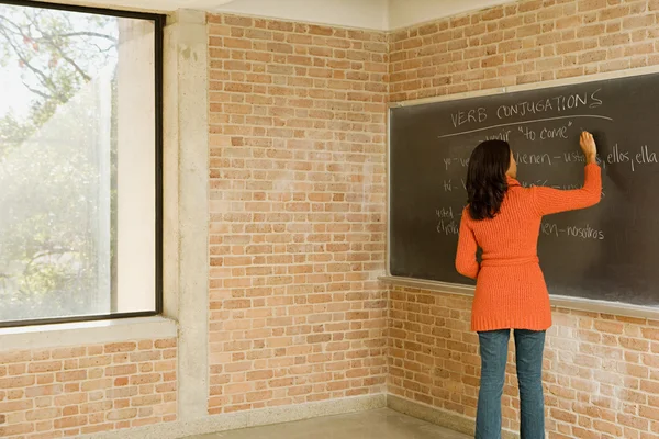 Teacher writing spanish text on blackboard — Stock Photo, Image