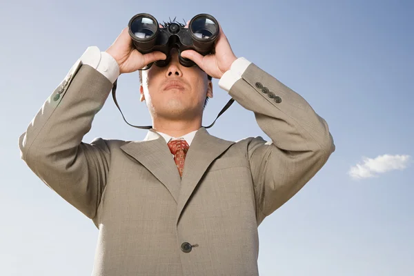 Businessman looking through binoculars in desert — Stock Photo, Image