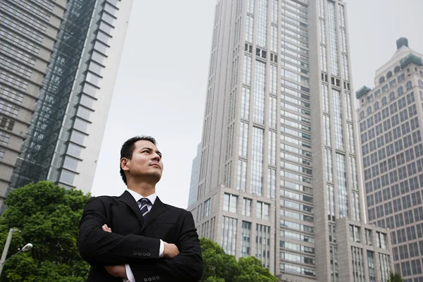 Allvarliga letar affärsman nära skyskrapor — Stockfoto