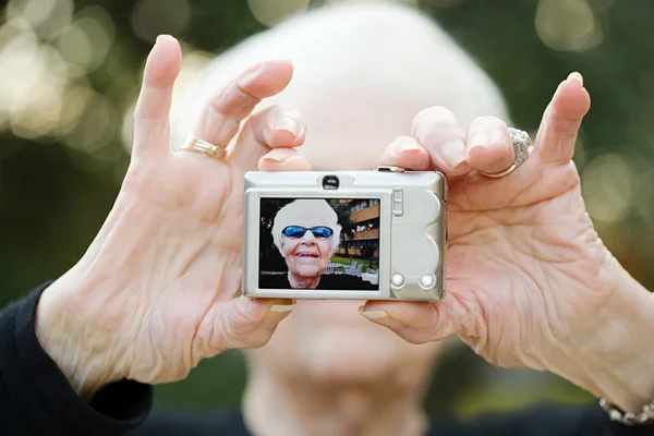 Äldre kvinna ta ett självporträtt fotografi — Stockfoto