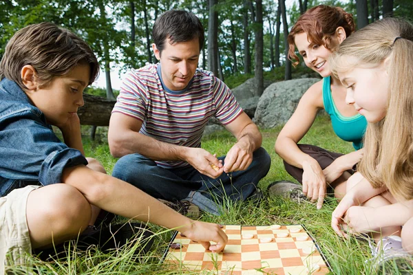 Familie spelen van dammen in bos — Stockfoto