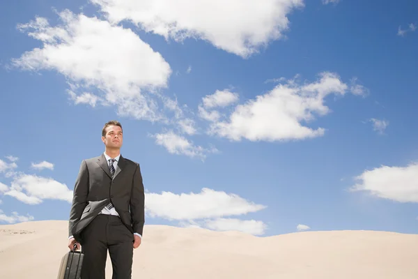 Businessman in desert under clouds sky — Stock Photo, Image