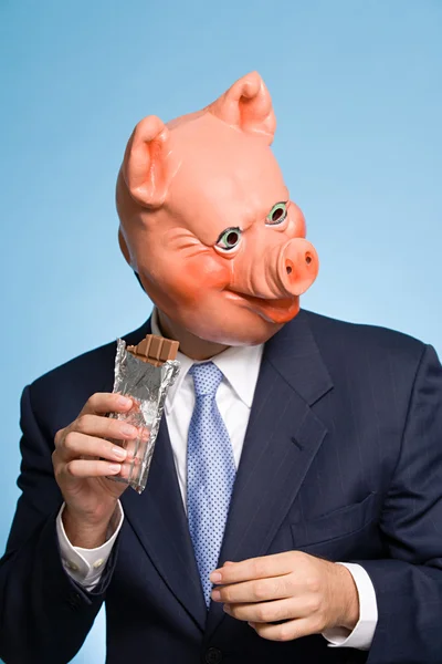 Man i en pig mask äta choklad — Stockfoto