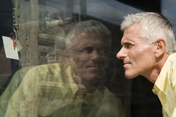 Мужчина смотрит на комод в витрине магазина — стоковое фото