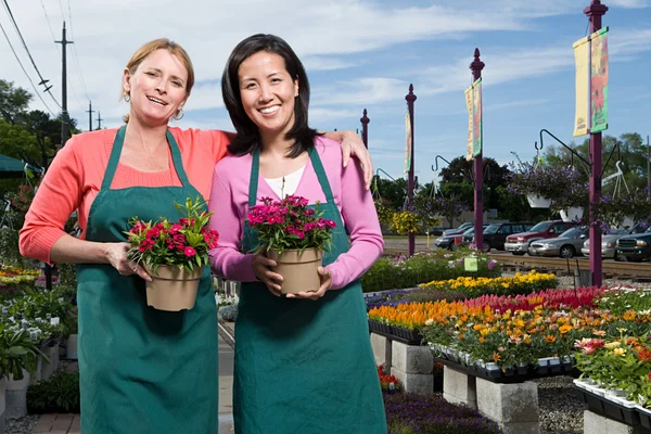 Dois assistentes de loja segurando flores — Fotografia de Stock