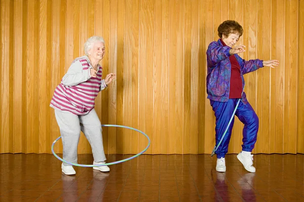 Hula hoops ile egzersiz iki üst düzey kadın — Stok fotoğraf