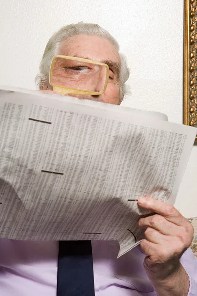 Homme lisant le journal avec loupe — Photo