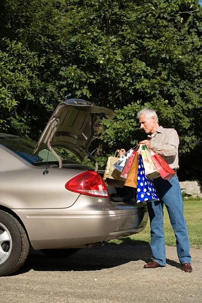 Homem colocando sacos de compras no carro — Fotografia de Stock