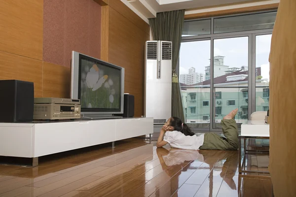 En tjej som tittar på tv i vardagsrummet — Stockfoto