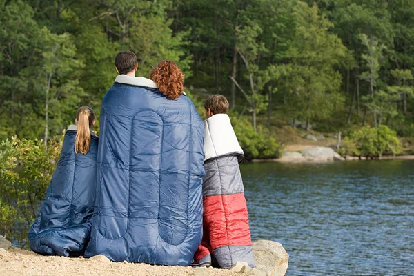 Family in sleeping bags by lake — Stock Photo, Image