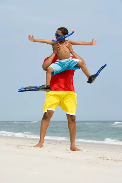 Father lifting son on beach Stock Picture