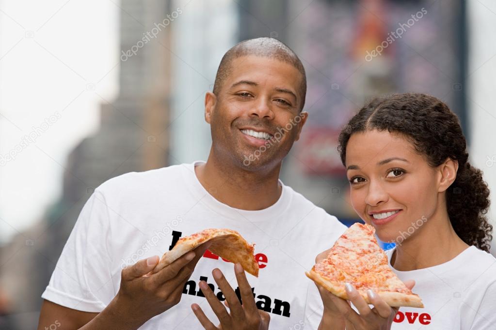 Couple holding pizza and smiling