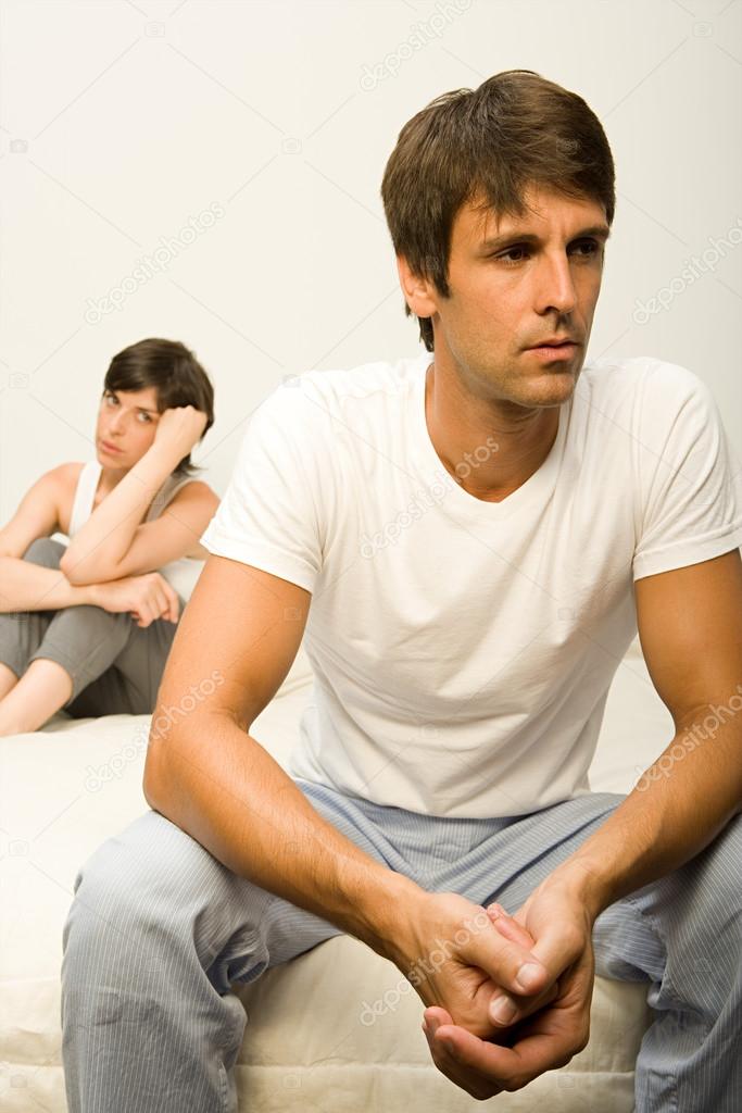 Couple arguing while sitting on bed
