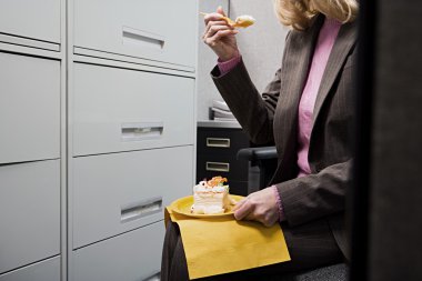 Businesswoman eating cake in secret clipart
