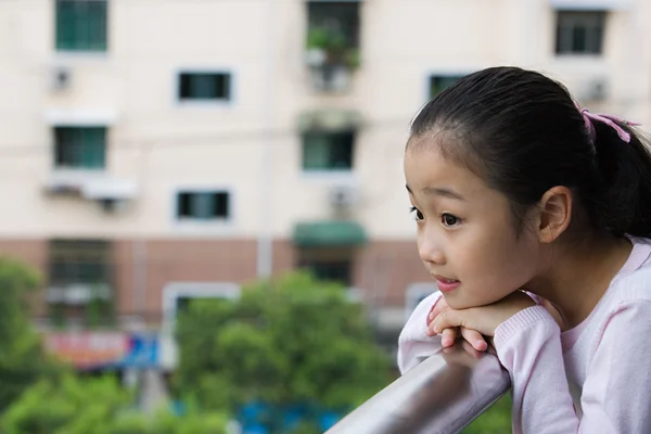 一个女孩靠在阳台上的栏杆 — 图库照片