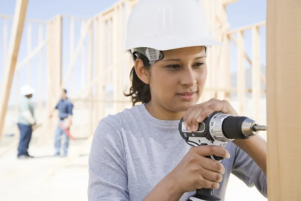 A female builder drilling wooden plank — Stock Photo, Image