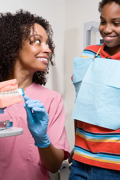 Enfermeira dentária mostrando menino como limpar os dentes corretamente — Fotografia de Stock