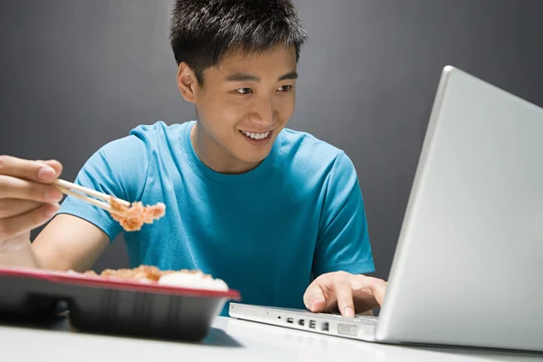 El hombre que trabaja en el ordenador portátil con comida para llevar —  Fotos de Stock
