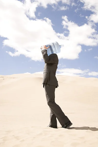 Businessman with bottle of water in desert — Stock Photo, Image