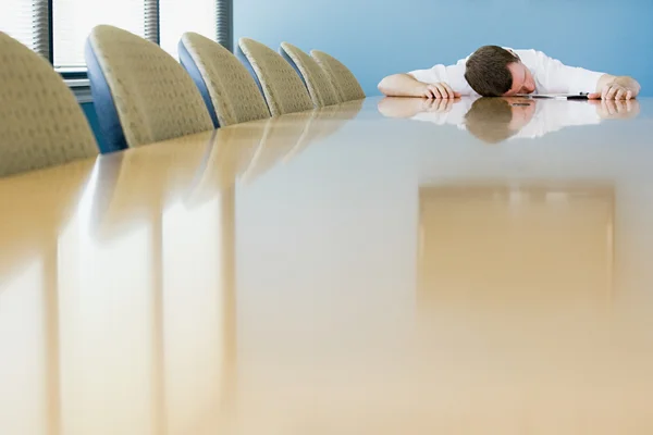 Человек спит на столе для конференций — стоковое фото