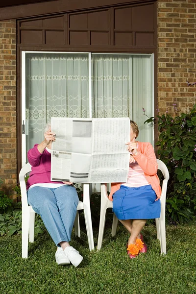 Two senior women sharing a newspaper — Stock Photo, Image