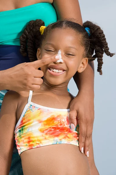 Mother putting suncream on daughters nose — Stock Photo, Image