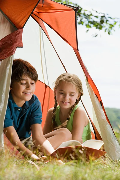 Boy and girl reading in a tent — Stock Photo, Image