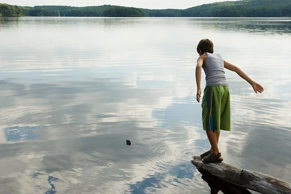 Chico jugando junto a un lago — Foto de Stock