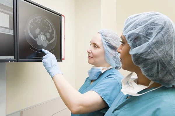 Surgeons looking at scan on computer monitor — Stock Photo, Image