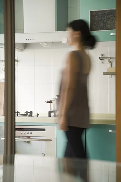 Uma jovem mulher andando em uma cozinha — Fotografia de Stock