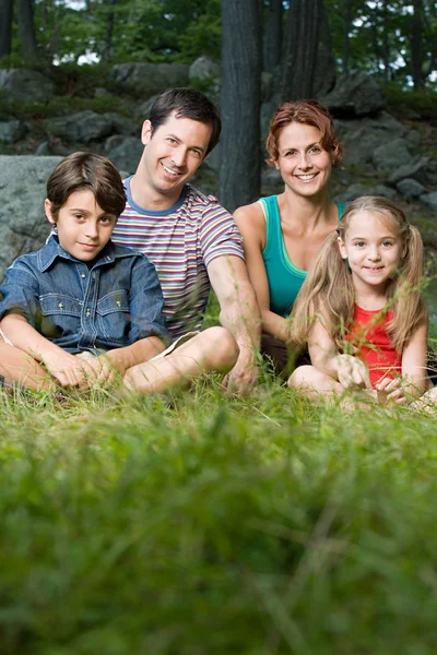 Família na floresta sentada na grama — Fotografia de Stock