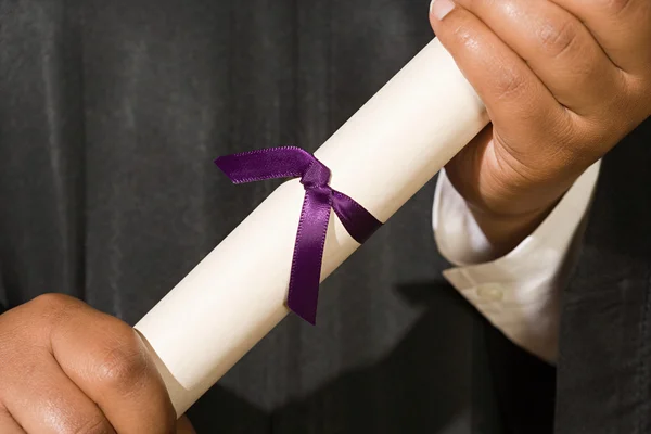 Graduado segurando diploma em mãos — Fotografia de Stock