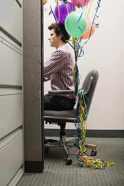 Zakenman met ballonnen gebonden aan zijn stoel — Stockfoto