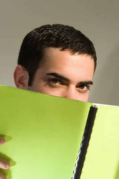 Männlicher Student versteckt sich hinter einem Buch — Stockfoto