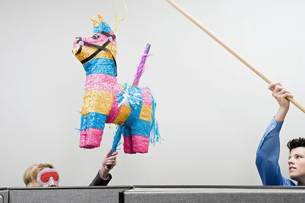 Office workers playing with a pinata — Stock Photo, Image