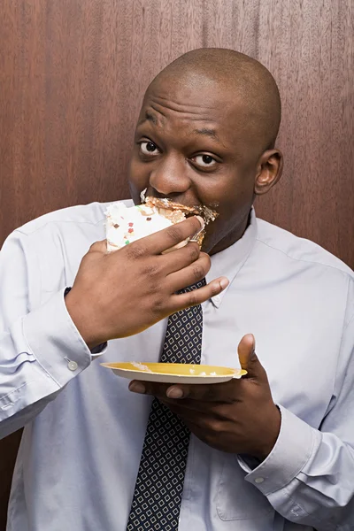 Businessman secretly eating cake — Stock Photo, Image