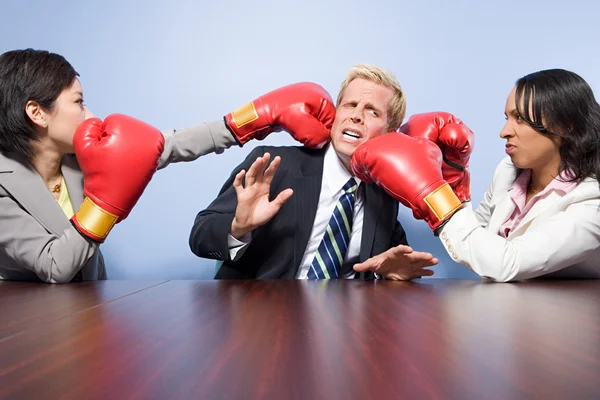 Two businesswomen punching a businessman — Stock Photo, Image