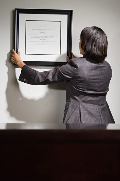 Mujer de negocios colgando certificado enmarcado —  Fotos de Stock