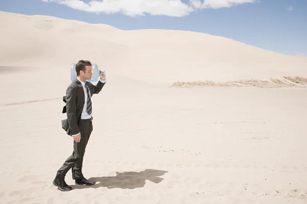 Man carrying water bottle in desert — Stock Photo, Image