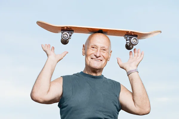 Senior man met een skateboard op zijn hoofd — Stockfoto