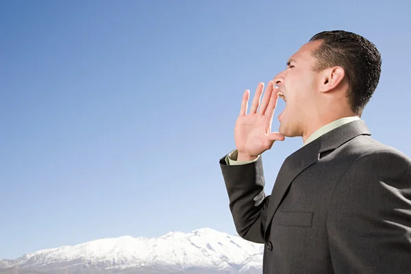 Businessman shouting by mountains — Stock Photo, Image