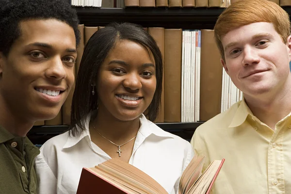 Drie studenten in de bibliotheek — Stockfoto