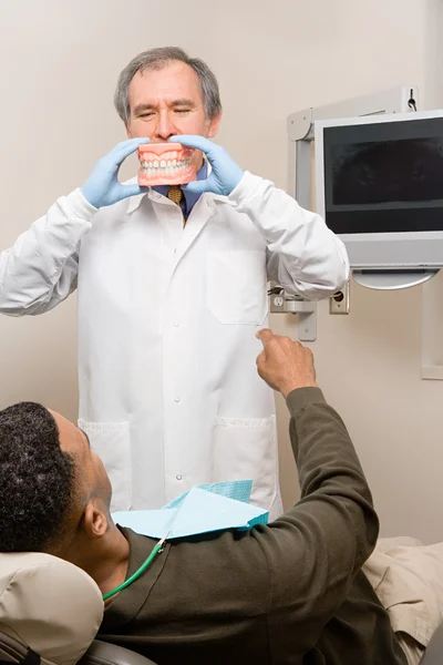 Dentist showing patient false teeth — Stock Photo, Image