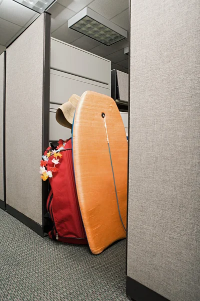 Suitcase and body board in office cubicle — Stock Photo, Image