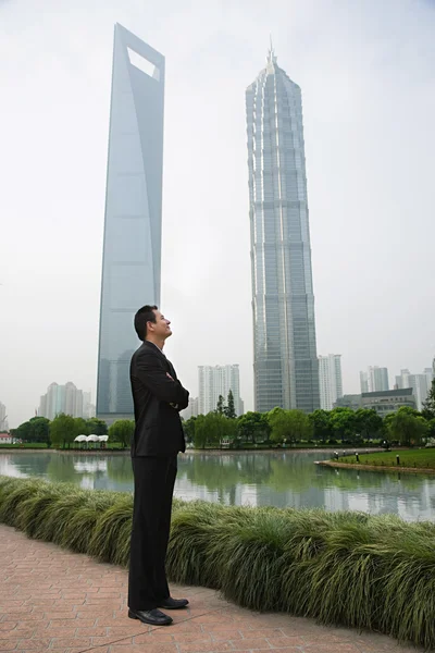 Businessman standing near skyscrapers — Stock Photo, Image