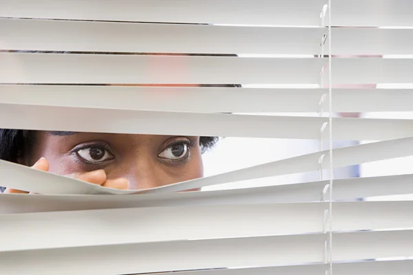 Mujer mirando a través de persianas —  Fotos de Stock