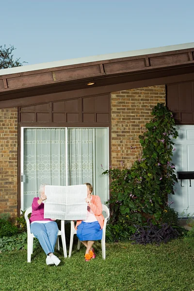 Two senior women sharing a newspaper — Stock Photo, Image