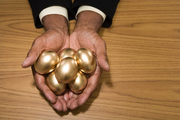 Чоловік тримає золоті яйця — стокове фото