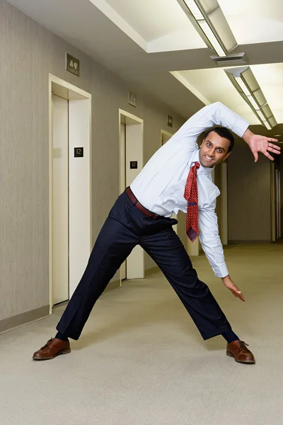 Office worker stretching in corridor — Stock Photo, Image